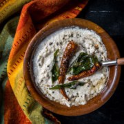 Coconut chutney served in a brown bowl tempered with red chilies and curry leaves.