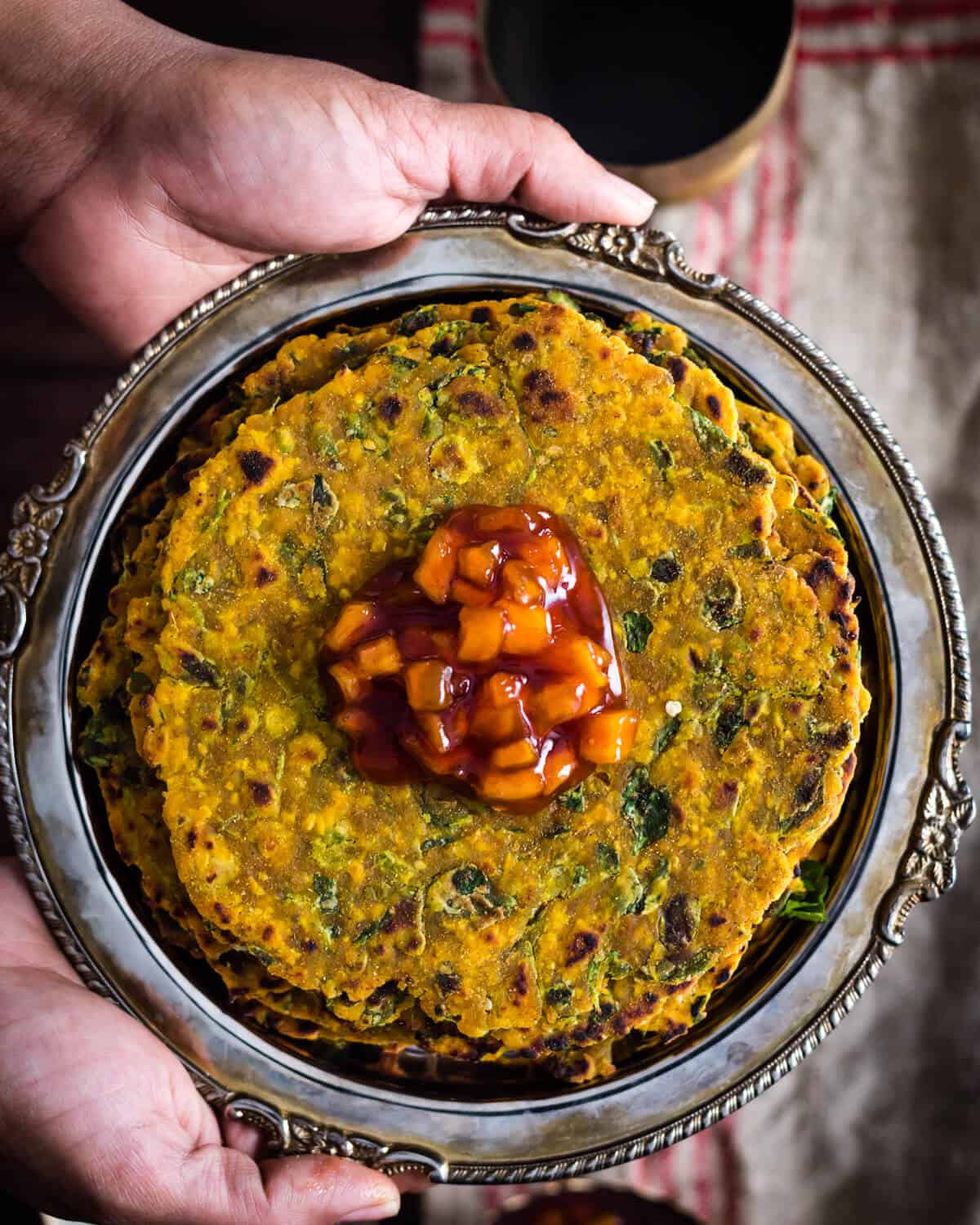 Methi thepla served in a metal plate with chundo on top
