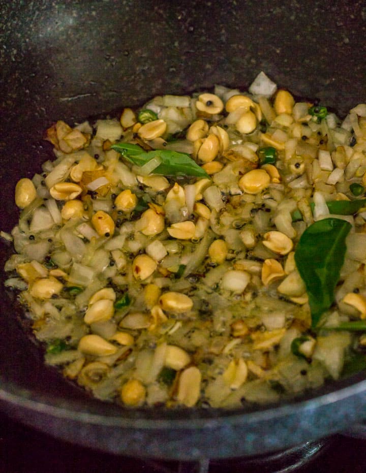 Onions being fried with peanuts and curry leaves