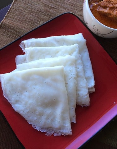 Neer dosa layered on red plate