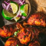 Tandoori chicken served with a side of lemon wedges, sliced onions and naan