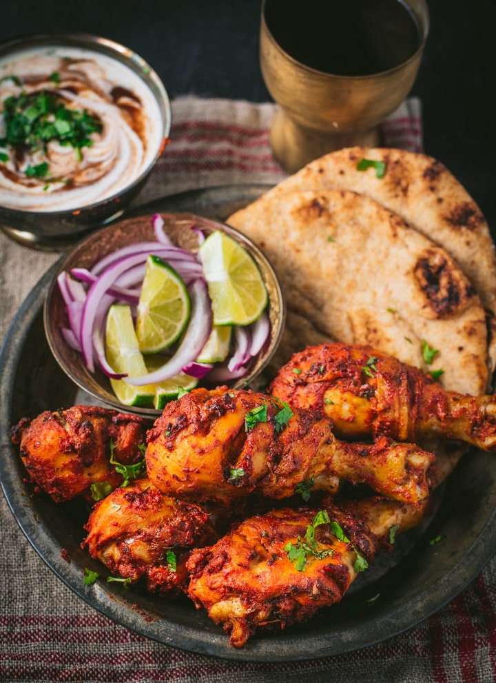 Tandoori chicken served with naan and side of lemon wedges and sliced onions