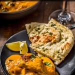An overhead shot of chicken tikka masala served in a black plate with garlic naan