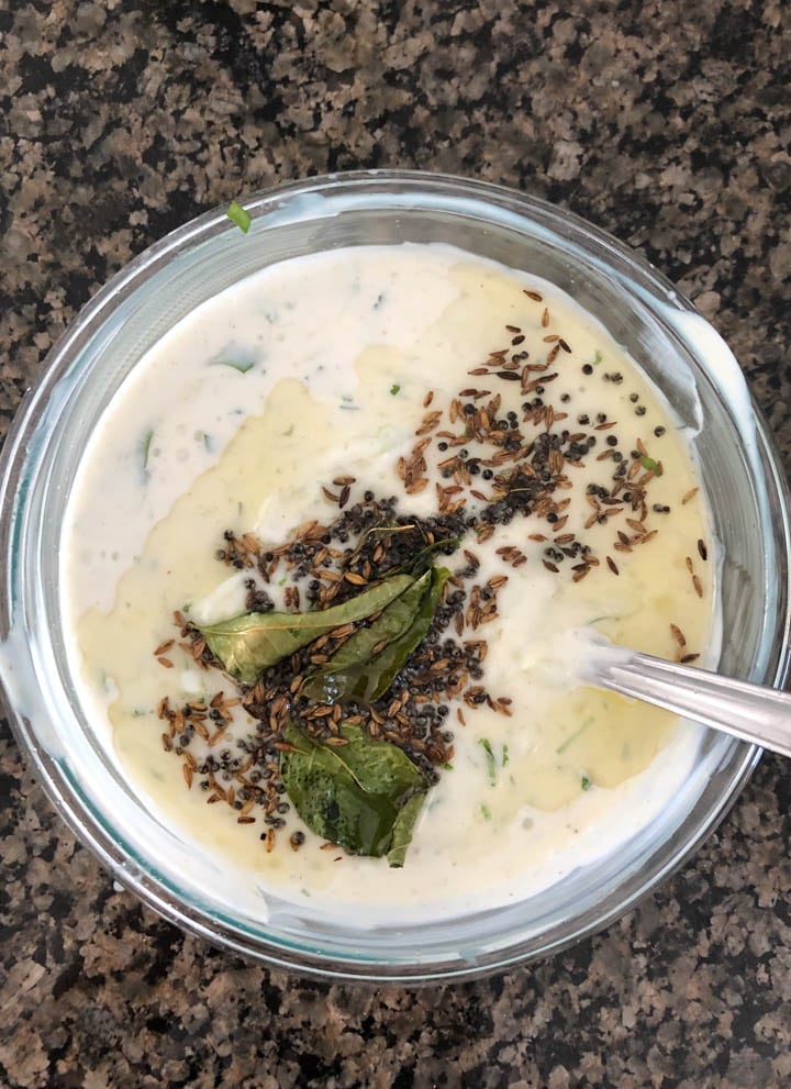 A tempering of curry leaves, cumin seeds, mustard seeds and oil are added to yogurt
