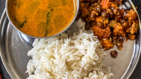Rice served with kadle suran and rasam in a steel plate