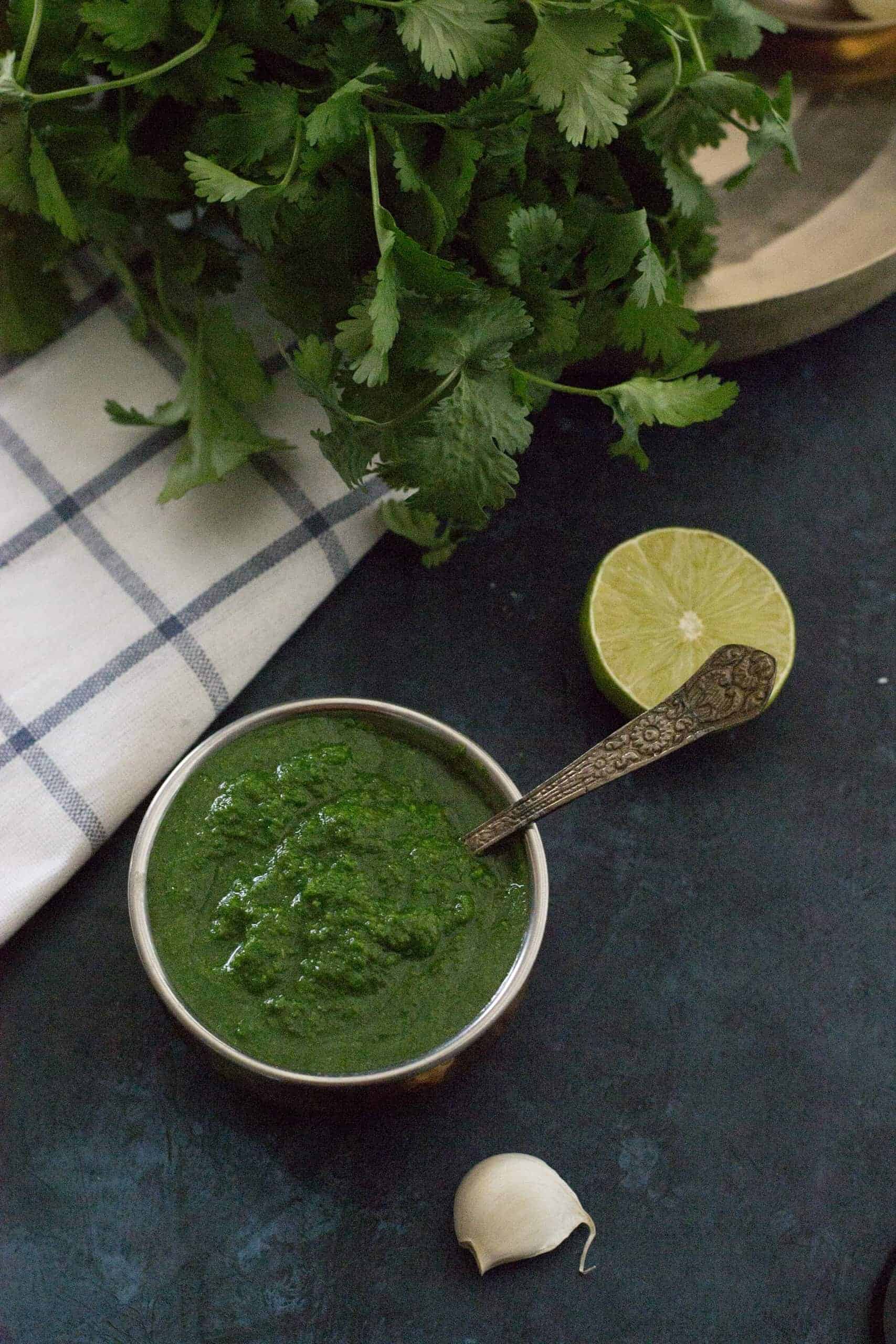 Coriander or cilantro chutney pictured with ingredients such as lime, coriander and garlic