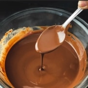 The words Homemade Magic Shell Sauce at the top with a picture of a glass bowl with magic shell sauce and a silver spoon dipped into the magic chocolate sauce.
