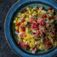 Corn chaat served in a blue bowl with sev