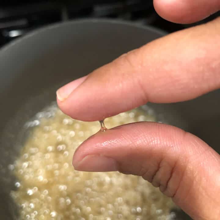One string consistency of sugar being demonstrated by placing sugar syrup between two fingers
