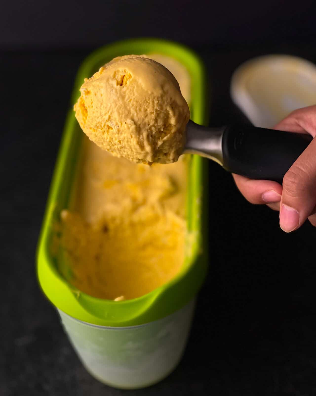 A person showing scooped Mango ice cream 