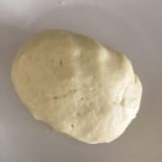 A dough ball in a silver bowl.