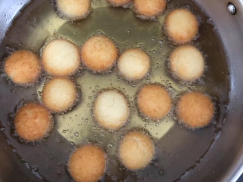Many dough balls frying in the oil.