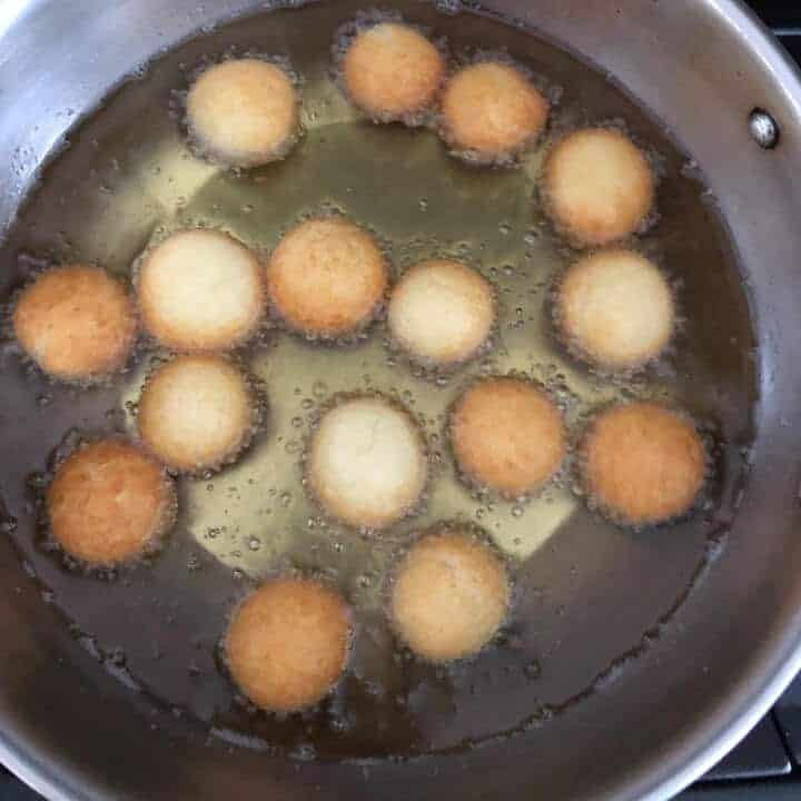 Many dough balls frying in the oil.
