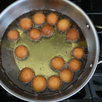 Gulab jamun frying on the other side in the pan.