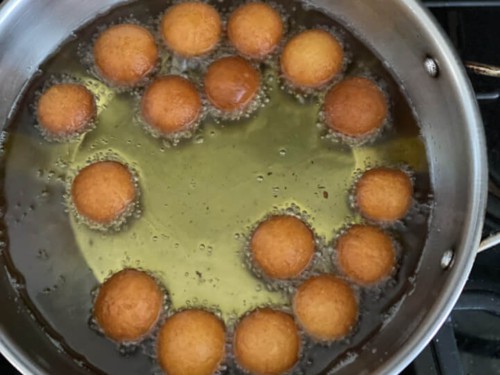 Gulab jamun frying on the other side in the pan.