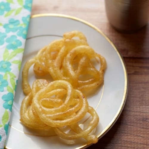 Jalebis placed on a white plate with a napkin on the left side