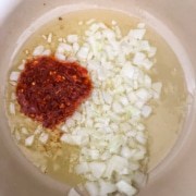 A pot with oil, onion, and garlic chili paste.