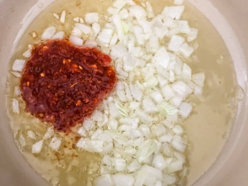 A pot with oil, onion, and garlic chili paste.