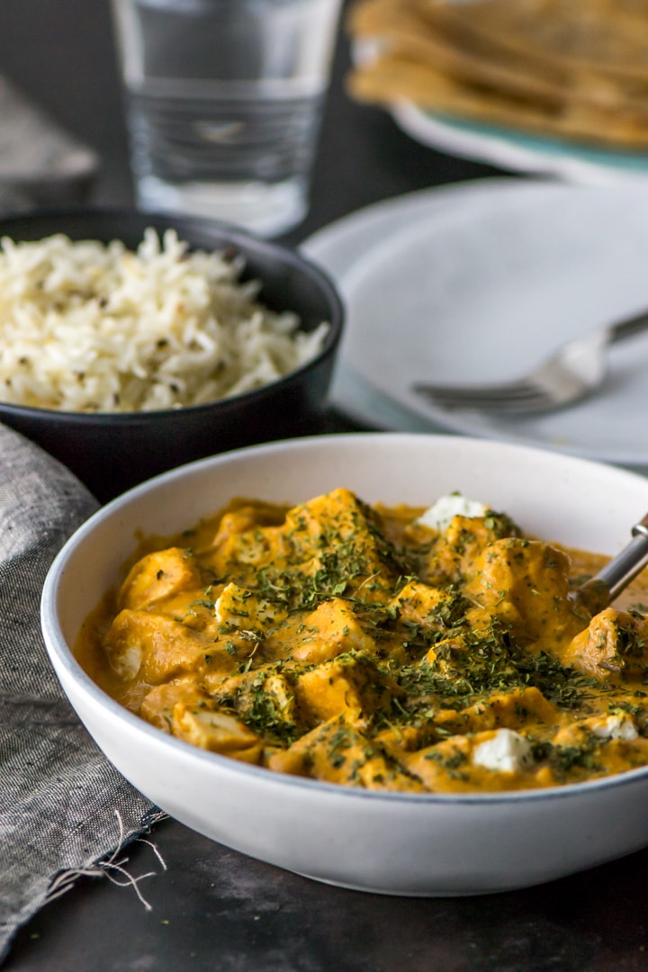 Paneer Makhani served in a white bowl sprinkled with roasted fenugreek leaves