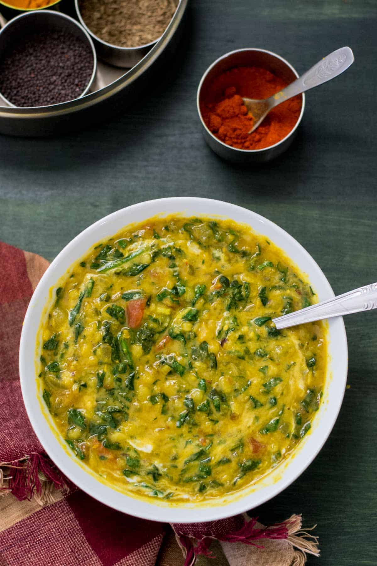 This mildly spiced, creamy version of Spinach and Tomato Dal (Dal Palak) makes for a delicious main course over hot cooked rice; it can also be served as a side dish.