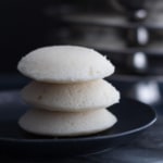 Three idlis stacked in a black plate