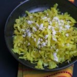 Cabbage stir fry topped with grated coconut served in a black bowl