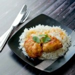 Mangalorean baked chicken topped with cilantro served over a bed of rice in a black plate 