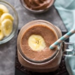 Overhead shot of banana nutella smoothie in a mason jar with a striped blue and white straw
