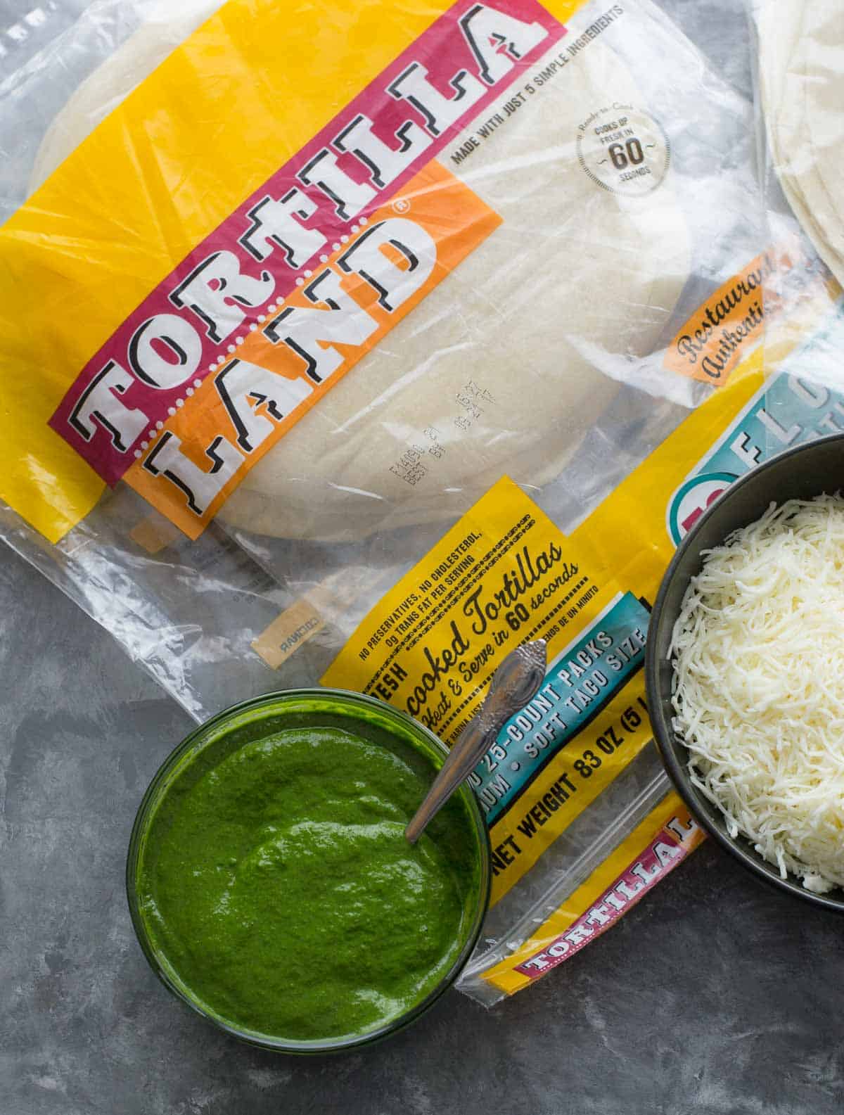 Tortillas in a plastic packet with text Tortilla land. Green chutney and grated cheese are on the side. 