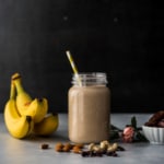 A mason jar with smoothie with banana, cashews, raisins and dates on the side