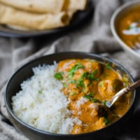 Chicken makhani served in a black bowl with rice and served with roti