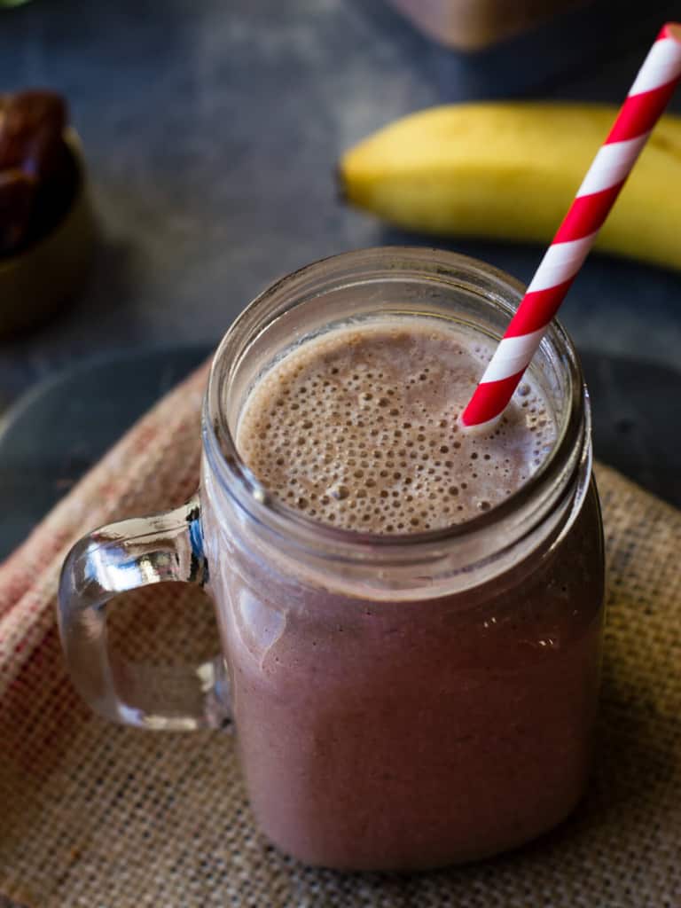 chocolate smoothie in a mason jar with straw and banana on the side