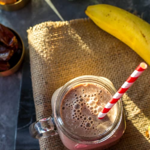 chocolate smoothie in a mason jar with straw on a burlap napkin