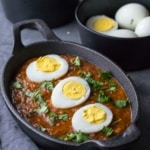 Egg curry served in a cast-iron pan with halved eggs as topping