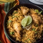 Chicken biryani served in a black bowl with lime wedges on top