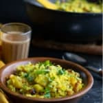 Poha served in a brown bowl accompanied by tea