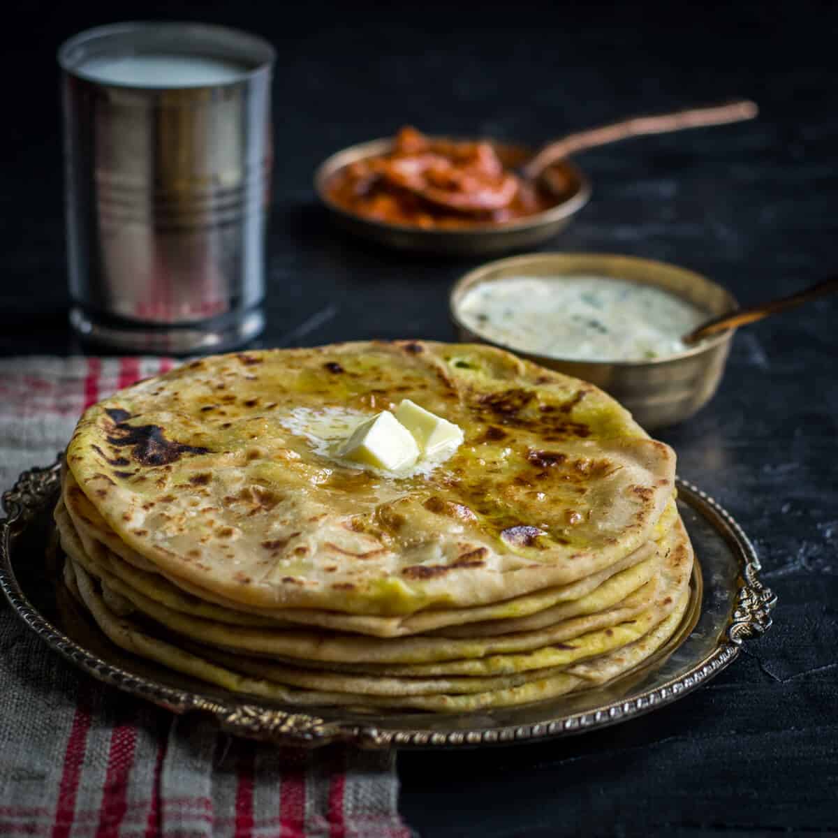Aloo paratha served with raita, pickle and lassi