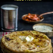 Aloo paratha served with a dollop of butter and accompanied by lassi, pickle and raita