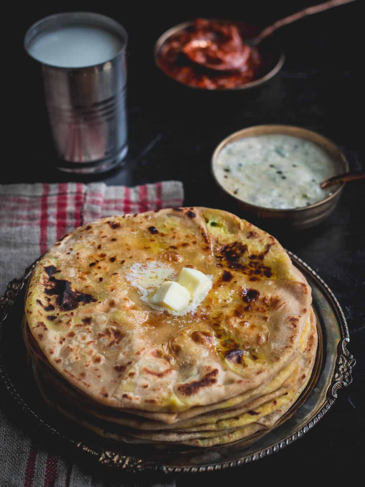 Aloo paratha served with lassi, pickle, raita and dollop of butter