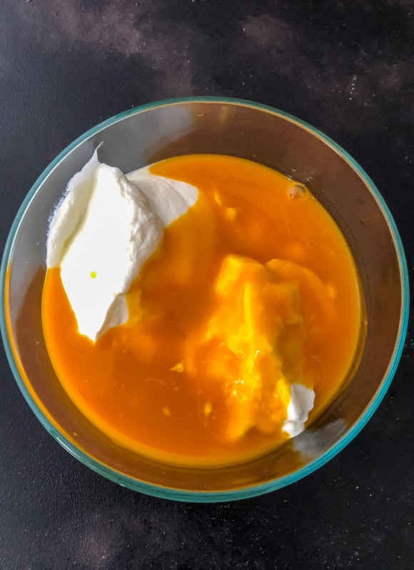 Yogurt being mixed with pulp to make Mango raita