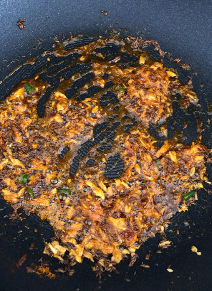 Stirring spices in a wok for Aloo Jeera recipe