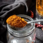 Rasam powder in a spoon placed on a glass bottle