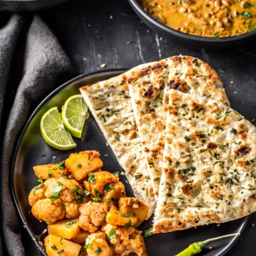 Aloo gobi served with garlic naan, green chili and lime wedges