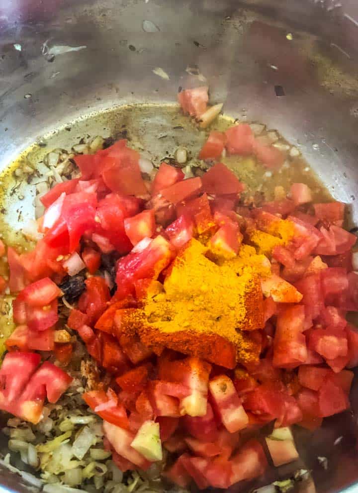 Tomatoes along with turmeric, chili powder and salt are added to the onion mixture.