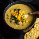 Potato corn chowder soup served in a black bowl with crackers