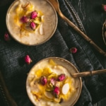 Two small bowls of Rice Kheerr on a black folded up napkin on an oval silver tray with two spoons and a small bowl of mixed nuts to the right. The words Rice Payasm Instant Pot Rice Kheer at the top.