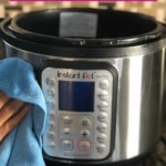 A blue microfiber cloth is being used to clean Instant Pot