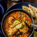 An overhead shot of Indian chicken curry served with naan, rice and lemon wedges