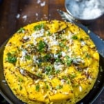 An overhead shot of khaman dhokla garnished with cilantro and grated coconut