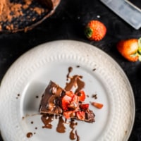 A white plate with a slice of instant pot brownies topped with strawberries.